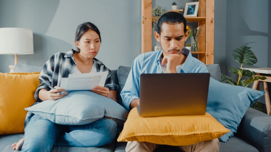 asian young couple man woman sit couch with laptop check documents